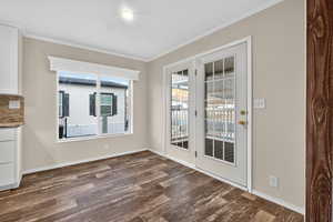 Unfurnished dining area with ornamental molding and dark wood-style floors