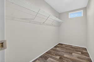 Walk in closet with dark wood-style flooring