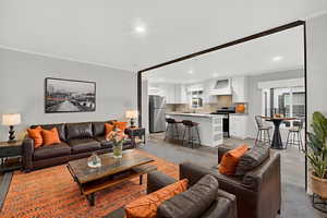 *Virtually staged* Living area with ornamental molding, light wood-style flooring, and recessed lighting