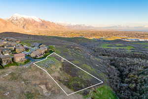 Aerial view of property's location with property parcel outlined, a mountain backdrop, and nearby suburban area