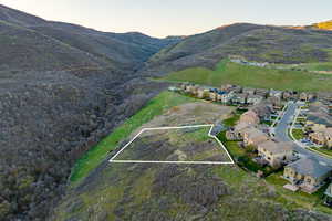 Aerial view at dusk of property parcel outlined, a mountain view, and a residential view