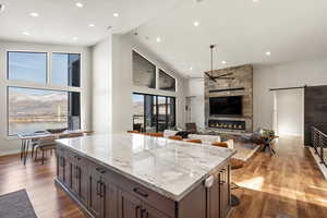 Kitchen with a barn door, a fireplace, light stone counters, light wood-type flooring, and a center island
