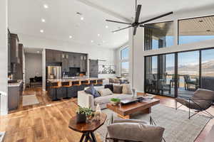 Living room featuring light wood-type flooring, high vaulted ceiling, recessed lighting, and ceiling fan