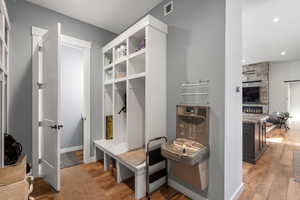 Mudroom featuring a stone fireplace and light wood finished floors