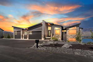 Modern home with stone siding, an attached garage, and driveway