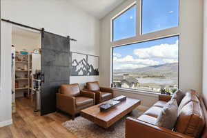Living area with a barn door, wood finished floors, a water view, and a towering ceiling