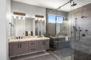 Full bath with a shower stall, double vanity, and light tile patterned floors