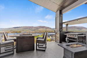 View of patio with a fire pit, a grill, and a water and mountain view