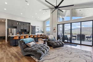Living room with high vaulted ceiling, light wood-type flooring, recessed lighting, a mountain view, and a ceiling fan