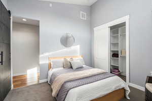Bedroom featuring a barn door, a closet, carpet flooring, recessed lighting, and vaulted ceiling