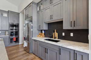 Kitchen with gray cabinets, glass insert cabinets, and appliances with stainless steel finishes