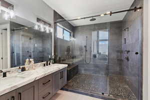 Full bath with double vanity, a shower stall, and light tile patterned floors