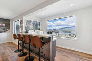 Indoor wet bar with light wood-style floors and light stone countertops