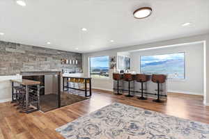 Bar with light wood finished floors, recessed lighting, light countertops, and a stone fireplace