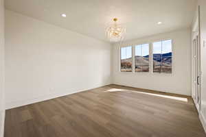 Unfurnished room featuring a mountain view, a chandelier, light wood-style floors, and recessed lighting