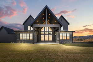Back of property featuring stone siding, board and batten siding, a lawn, and a patio