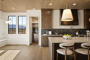 Kitchen featuring hanging light fixtures, light wood-style floors, recessed lighting, a breakfast bar area, and decorative backsplash