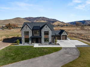 View of front of home with stone siding, a standing seam roof, a mountain view, and driveway