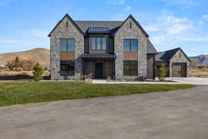 View of front facade with a mountain view, stone siding, a standing seam roof, and a front yard