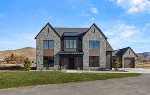 View of front of home with a mountain view, stone siding, a standing seam roof, and a metal roof