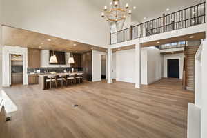 Living room with light wood-type flooring, a chandelier, recessed lighting, and a towering ceiling