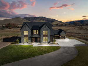 Modern farmhouse style home featuring stone siding, a standing seam roof, driveway, and a mountain view