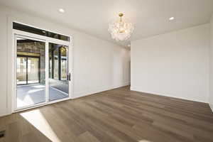 Spare room featuring wood finished floors, recessed lighting, and a chandelier