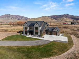 French country home with stone siding, a mountain view, driveway, a front yard, and a view of rural / pastoral area
