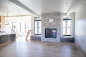 Unfurnished living room featuring beam ceiling, a fireplace, and light wood-style flooring