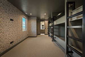 Unfurnished bedroom with a textured ceiling, carpet floors, wallpapered walls, and ensuite bath