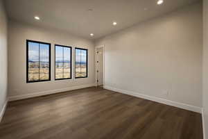 Empty room with dark wood finished floors and recessed lighting