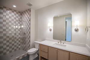 Bathroom featuring vanity, a shower stall, dark tile patterned flooring, and recessed lighting