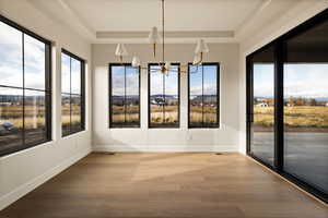 Unfurnished dining area with a chandelier, wood finished floors, and plenty of natural light