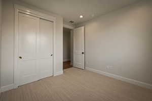 Unfurnished bedroom with light carpet, a closet, and recessed lighting