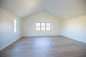 Empty room with plenty of natural light, wood finished floors, and high vaulted ceiling