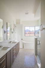 Full bathroom with a freestanding tub, double vanity, light tile patterned flooring, and a stall shower