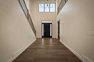 Foyer entrance featuring dark wood finished floors, a high ceiling, stairway, and a chandelier