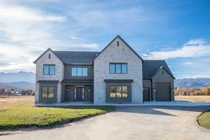 Modern inspired farmhouse with a mountain view, board and batten siding, concrete driveway, and stone siding