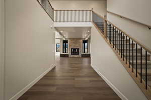 Hall with a towering ceiling, dark wood-type flooring, stairs, and recessed lighting