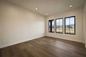 Empty room with dark wood-style flooring and recessed lighting