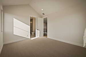 Unfurnished bedroom featuring carpet flooring, lofted ceiling, and ensuite bath