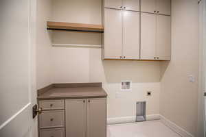 Washroom featuring hookup for a washing machine, hookup for an electric dryer, and cabinet space