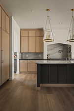 Kitchen with hanging light fixtures, dark wood-type flooring, a textured ceiling, decorative backsplash, and dark stone countertops