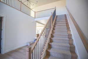 Staircase with wood finished floors, a high ceiling, and a chandelier