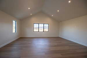 Spare room with high vaulted ceiling, dark wood-style flooring, and recessed lighting