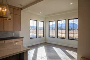 Unfurnished dining area with a mountain view, light wood-style floors, recessed lighting, and a raised ceiling
