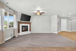 Unfurnished living room featuring arched walkways, a fireplace, light carpet, a ceiling fan, and a textured ceiling