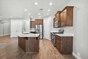 Kitchen with stainless steel appliances, arched walkways, a kitchen bar, recessed lighting, and a center island with sink
