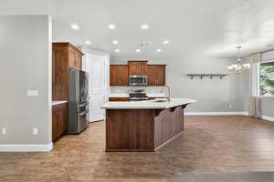 Kitchen with stainless steel appliances, recessed lighting, dark wood-type flooring, an island with sink, and hanging light fixtures