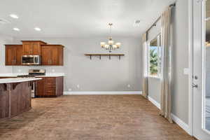Kitchen featuring a breakfast bar, appliances with stainless steel finishes, open shelves, decorative light fixtures, and a chandelier